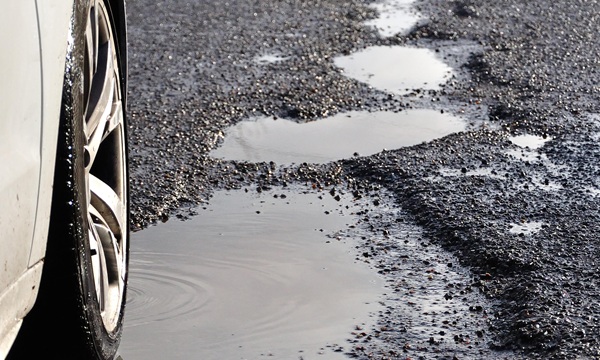 Wet potholes in road, Stanwell Moor, Surrey, England, United Kingdom