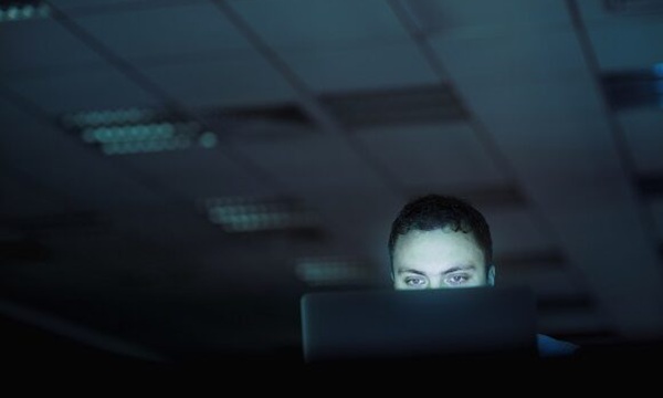 Man looking at laptop computer in office at night
