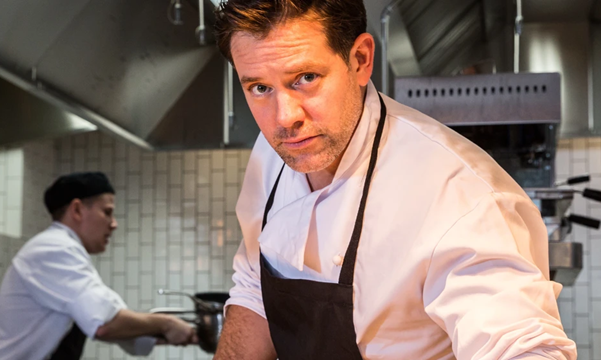 Matt Tebbutt cooking in a kitchen/Matt Tebbutt yn coginio mewn cegin